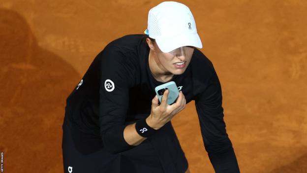 Iga Swiatek reacts to her mobile phone during a match at the Italian Open