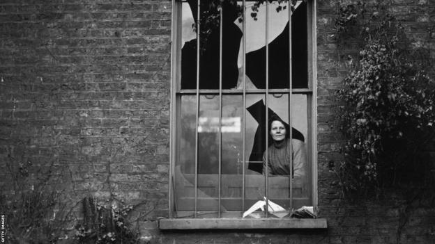 A woman peers through a shattered window at Holloway prison after a December 1913 bomb attack. The Women's Social and Political Union were suspected for being behind the attack