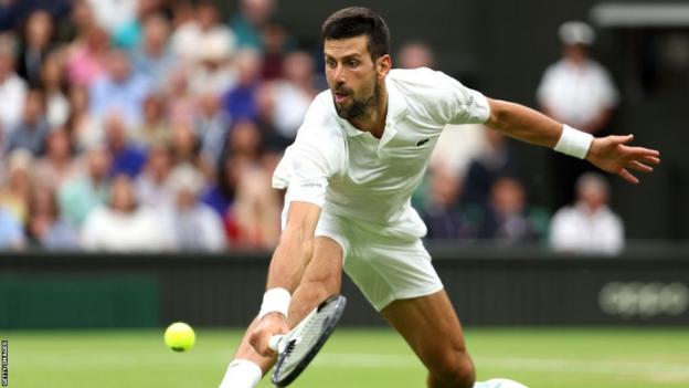 Novak Djokovic slides to reach a ball in the Wimbledon semi-finals